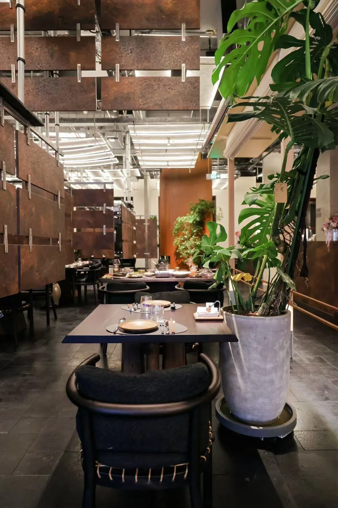 曼莉 MIX 西餐厅用餐区，绿植与悬挂金属隔断形成层次